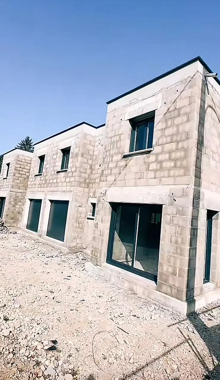 Élévation de murs maçonnés et ouvertures en cours de construction.
